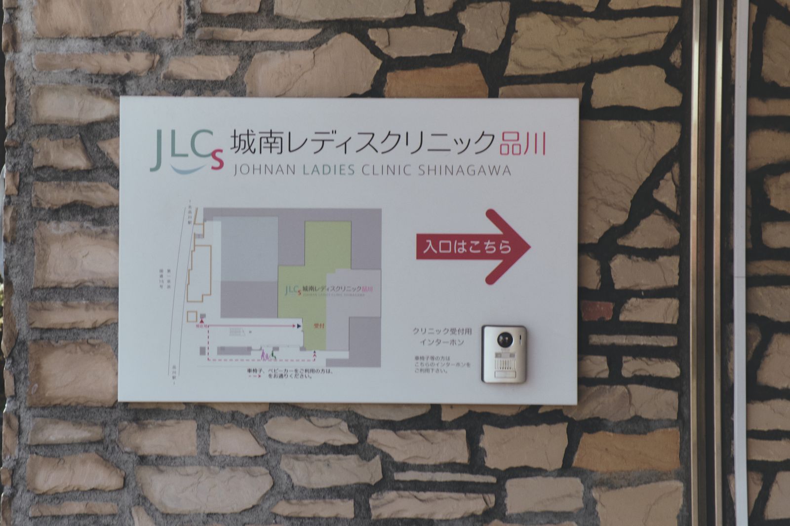 石壁の案内板。院名と敷地の地図、「入口はこちら」の矢印