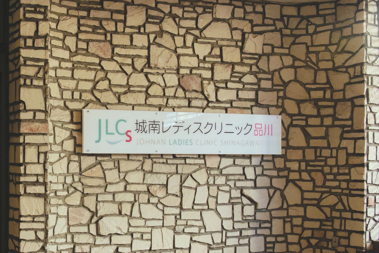 入口の角の石壁と、クリニックの院名の看板