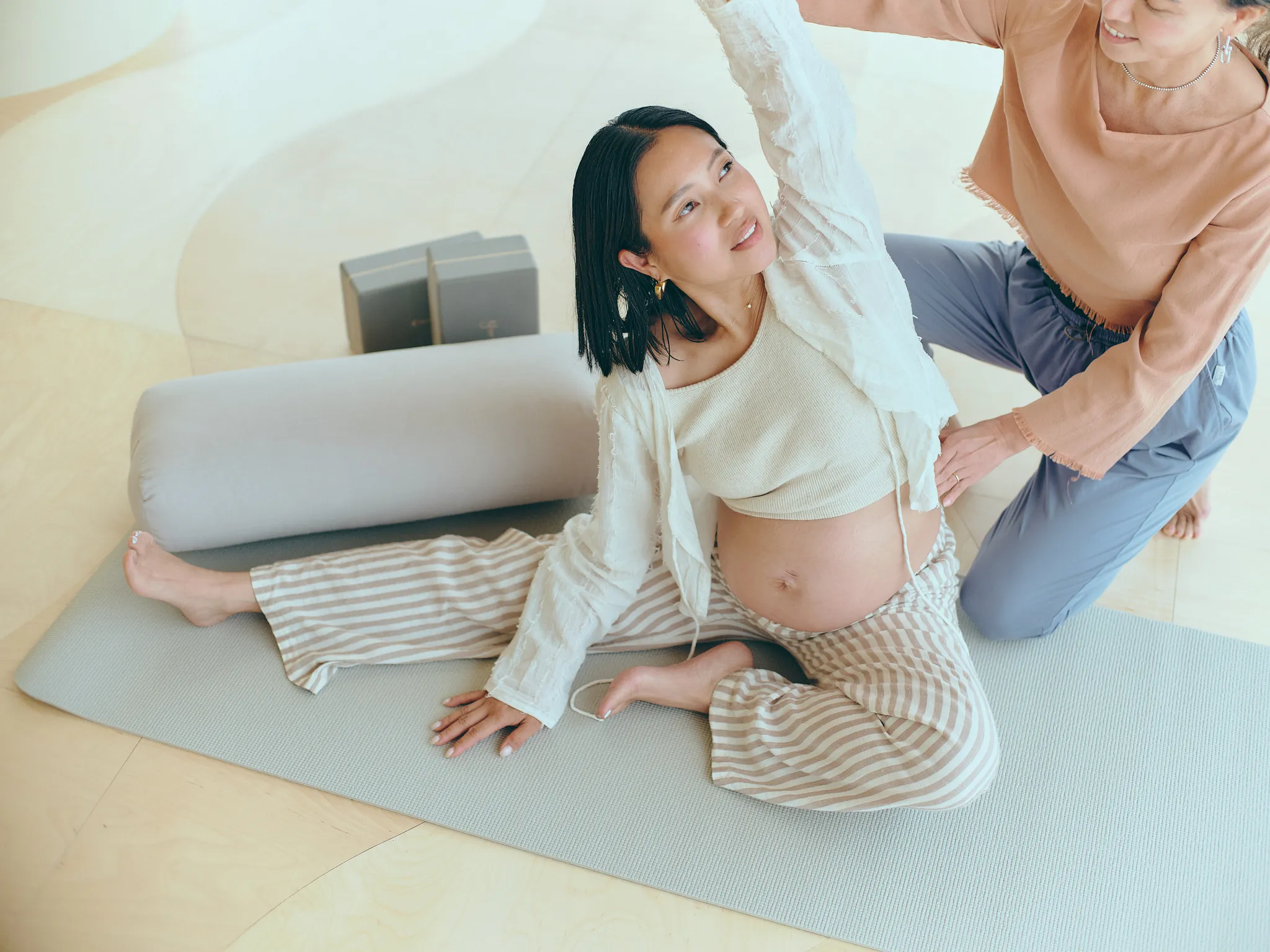 マタニティヨガのクラスで、インストラクターの指導を受けながら側屈ポーズを行う妊婦