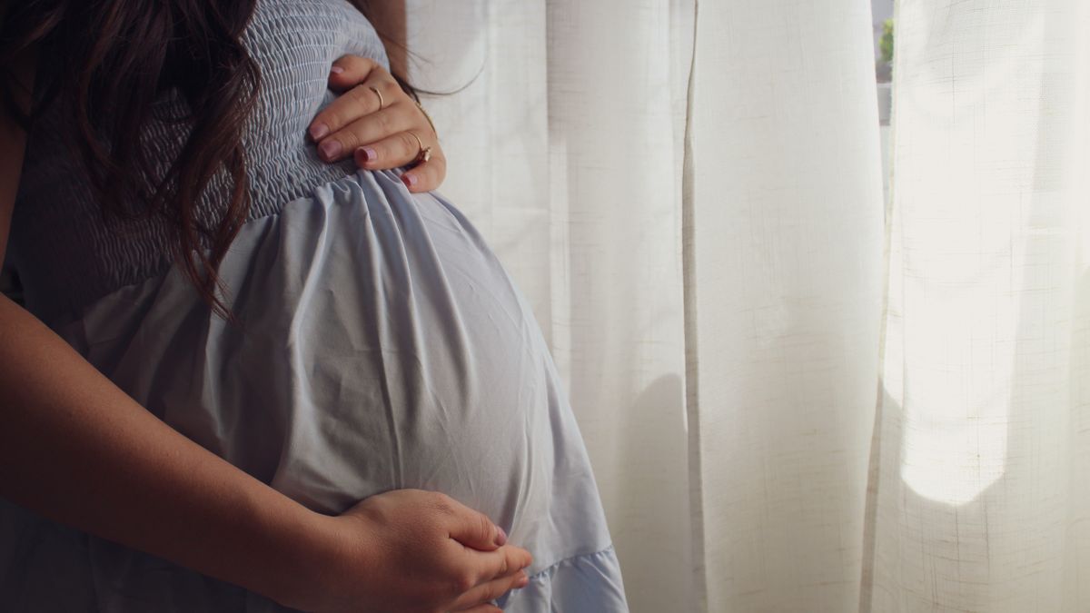 窓辺でおなかに手を添える妊婦さん｜東京・目黒のレディースクリニックなみなみ