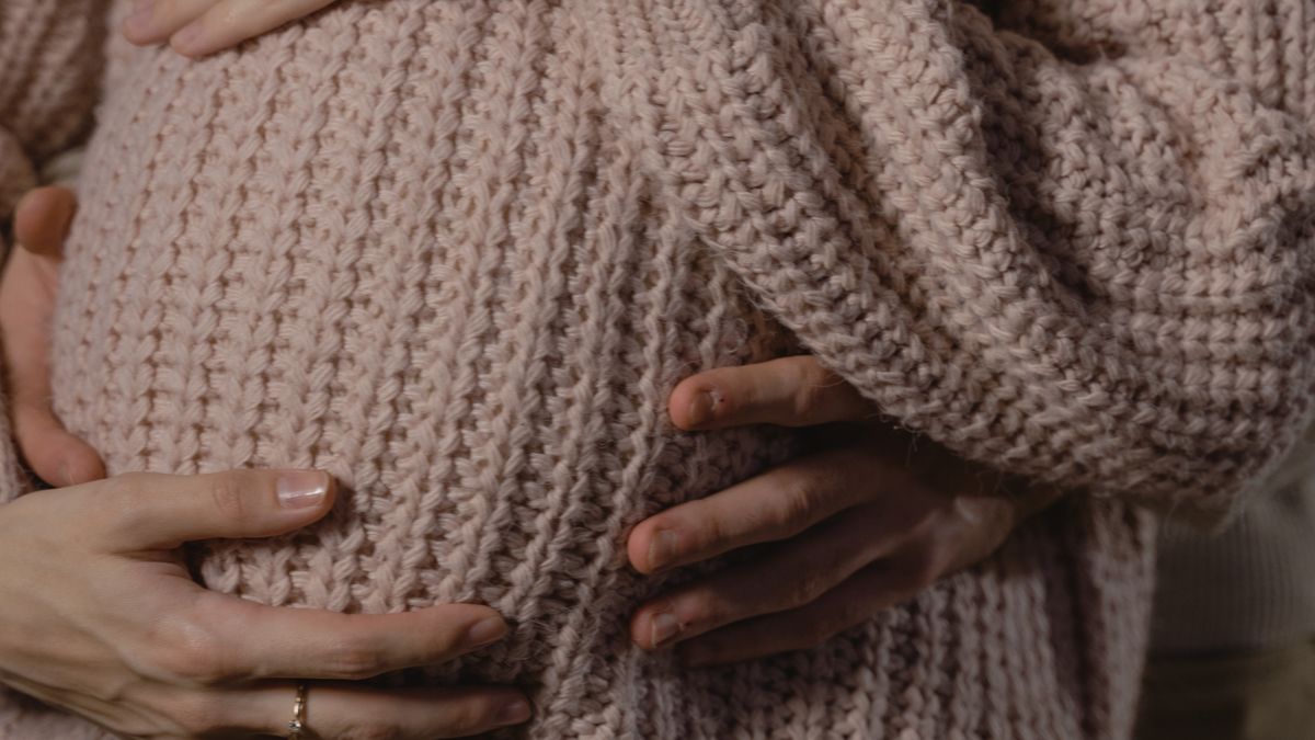 おなかに手を添える妊婦（里帰り出産の妊婦健診と費用助成のイメージ）